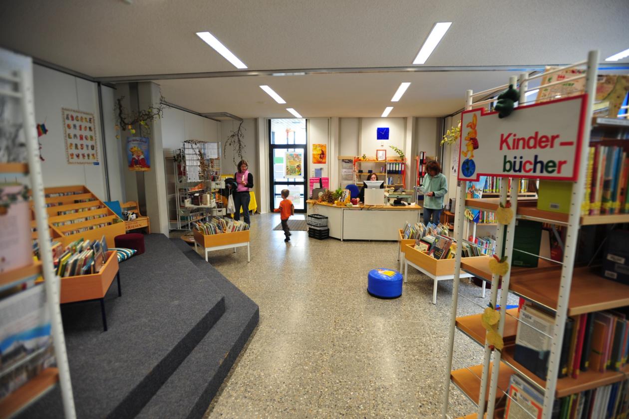 ein großer Raum mit Bücherregalen und einigen Lesern