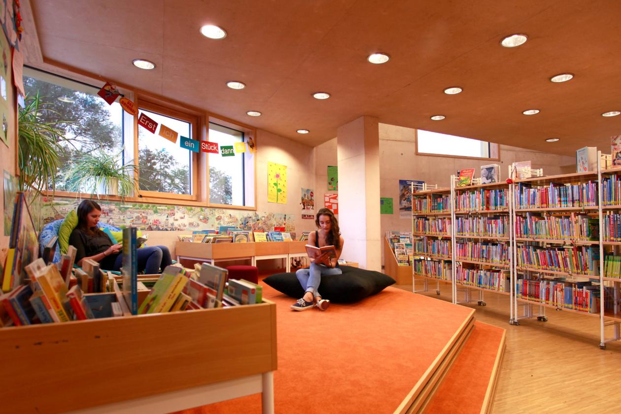 Im Kinderbereich sitzen zwei Leserinnen gemütlich und lesen Bücher.