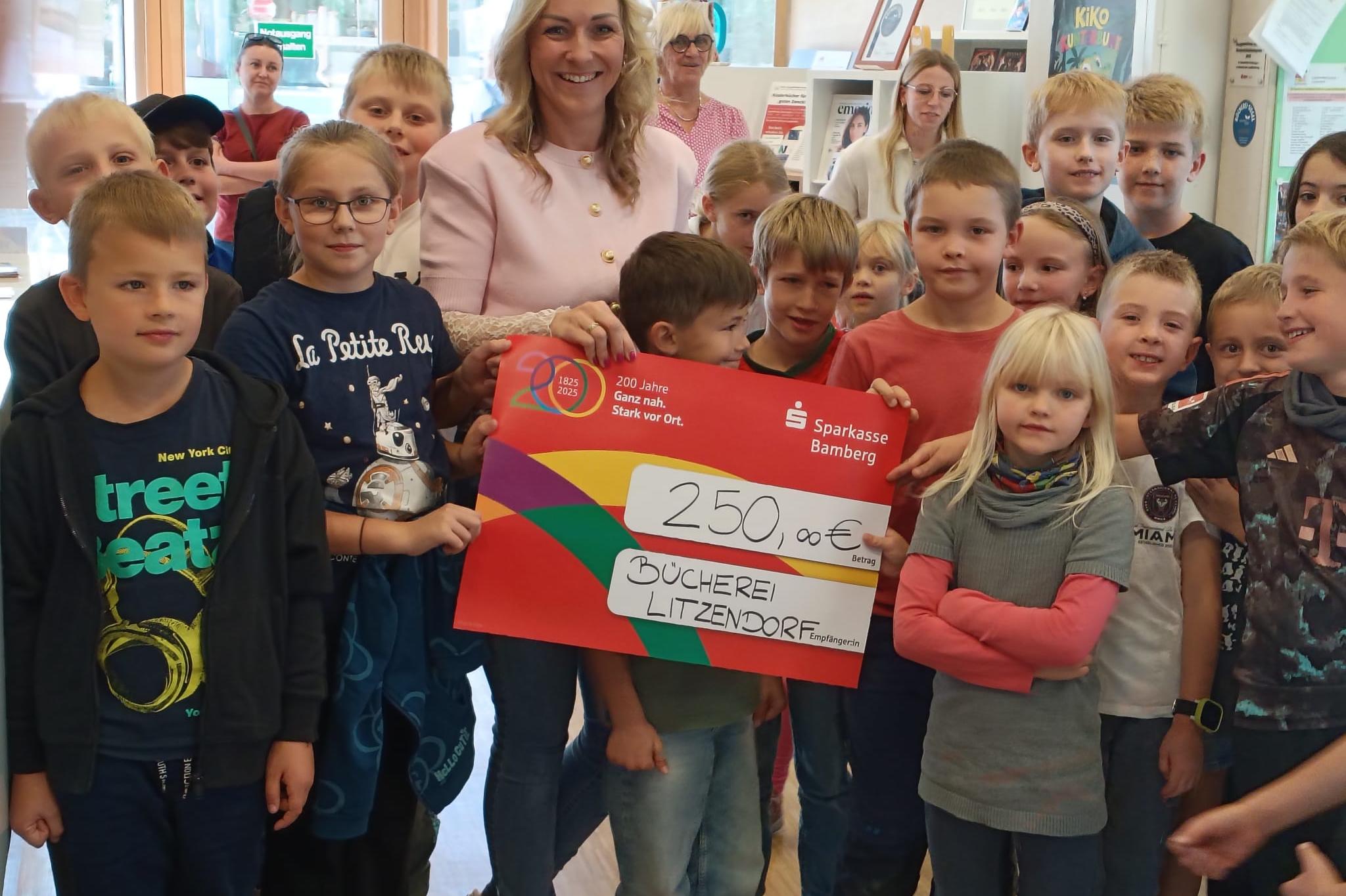 Scheckübergabe mit Mitarbeiterin der Bücherei und Kindern